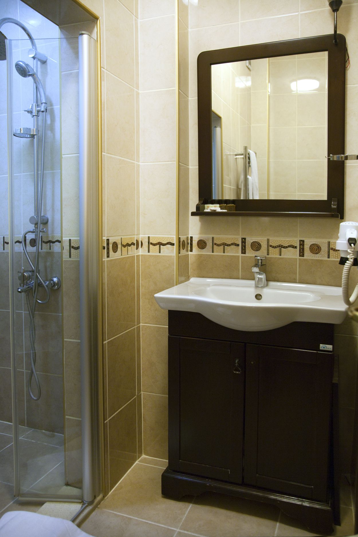 A bathroom with a glass-enclosed shower, a white sink, and a mirror above it.