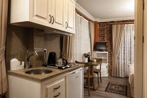A compact kitchen with a sink, stove, and a small dining area with a table and chairs.