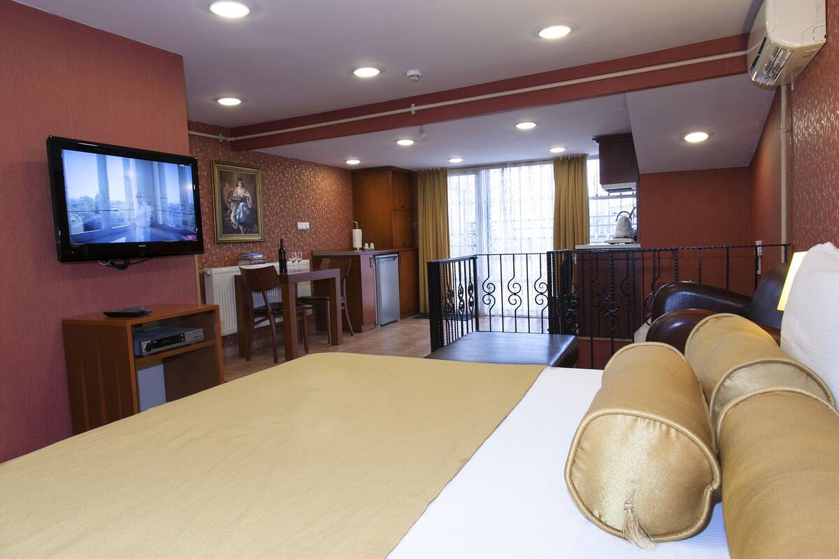A hotel room with a bed, a television, a desk, and a balcony.