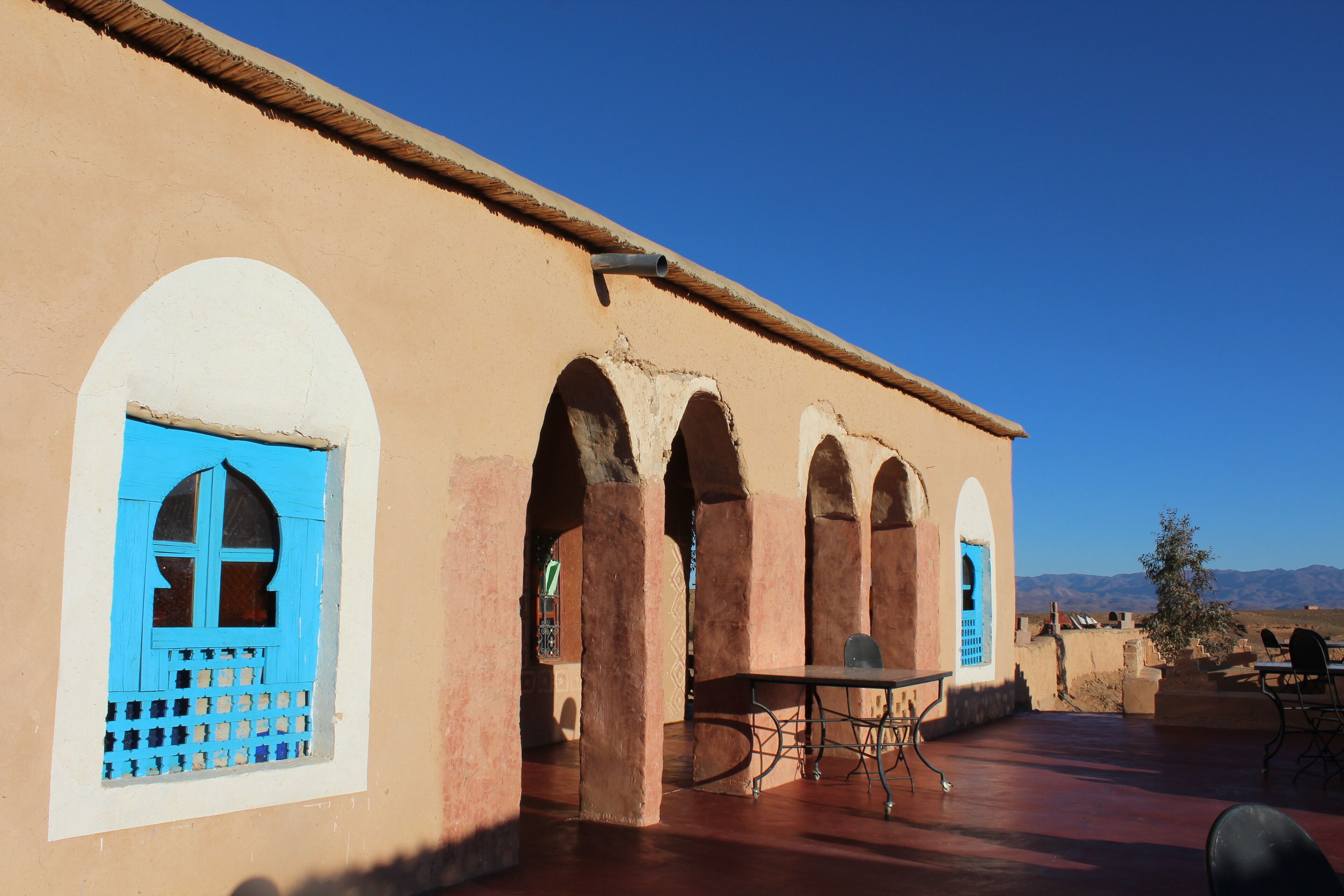 A building with arched windows and a table with chairs outside.