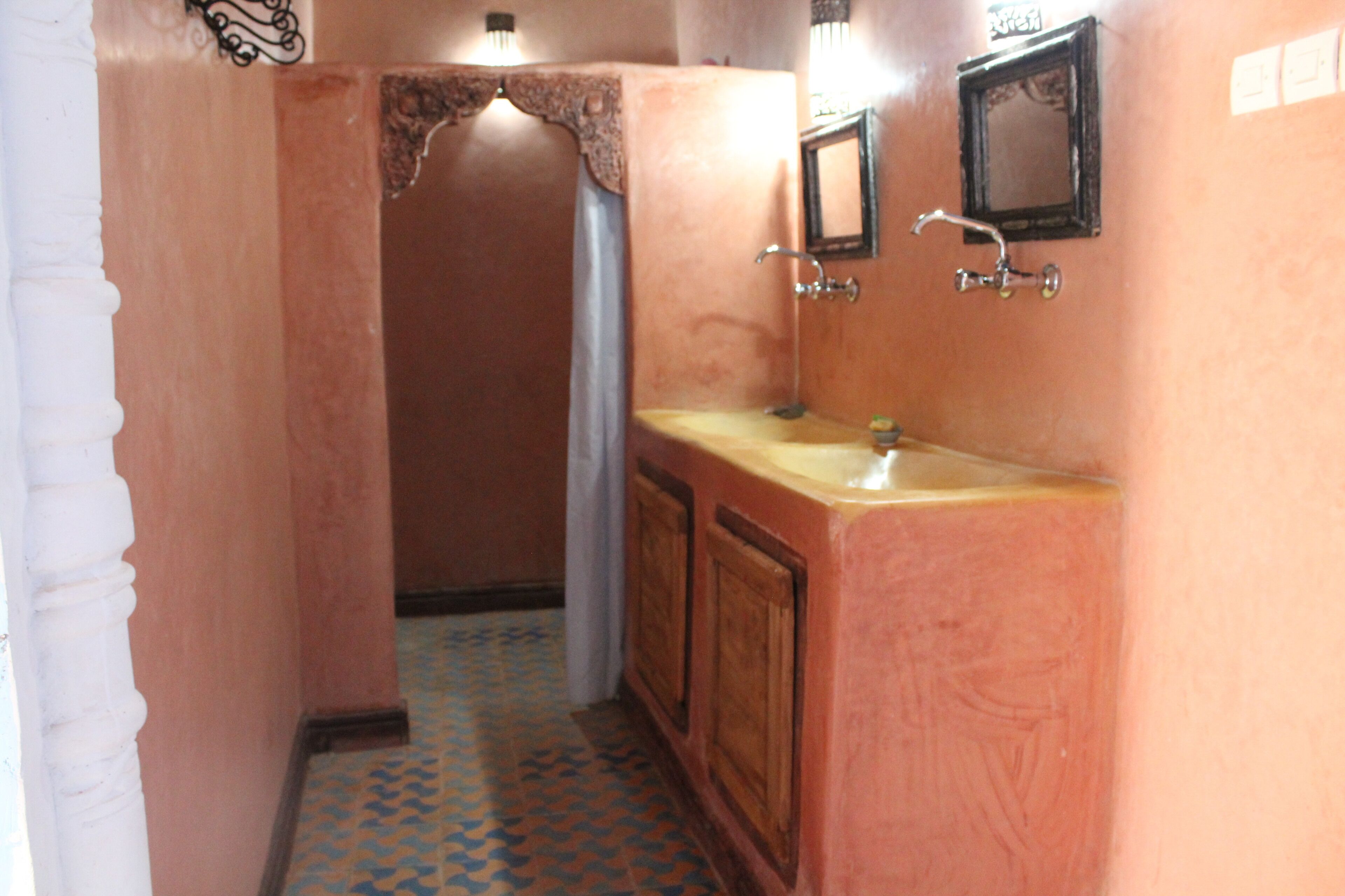 A narrow hallway with a bathroom featuring a wooden vanity, a sink, and a mirror.