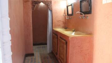 Un pasillo estrecho con un baño que tiene un tocador de madera, un lavabo y un espejo.