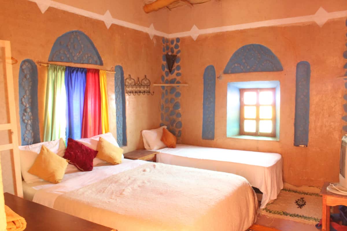 A room with two beds, a television, and a window with curtains.