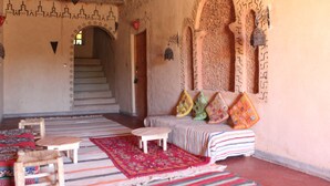 A traditional interior with a staircase, patterned walls, and a sofa with colorful cushions.