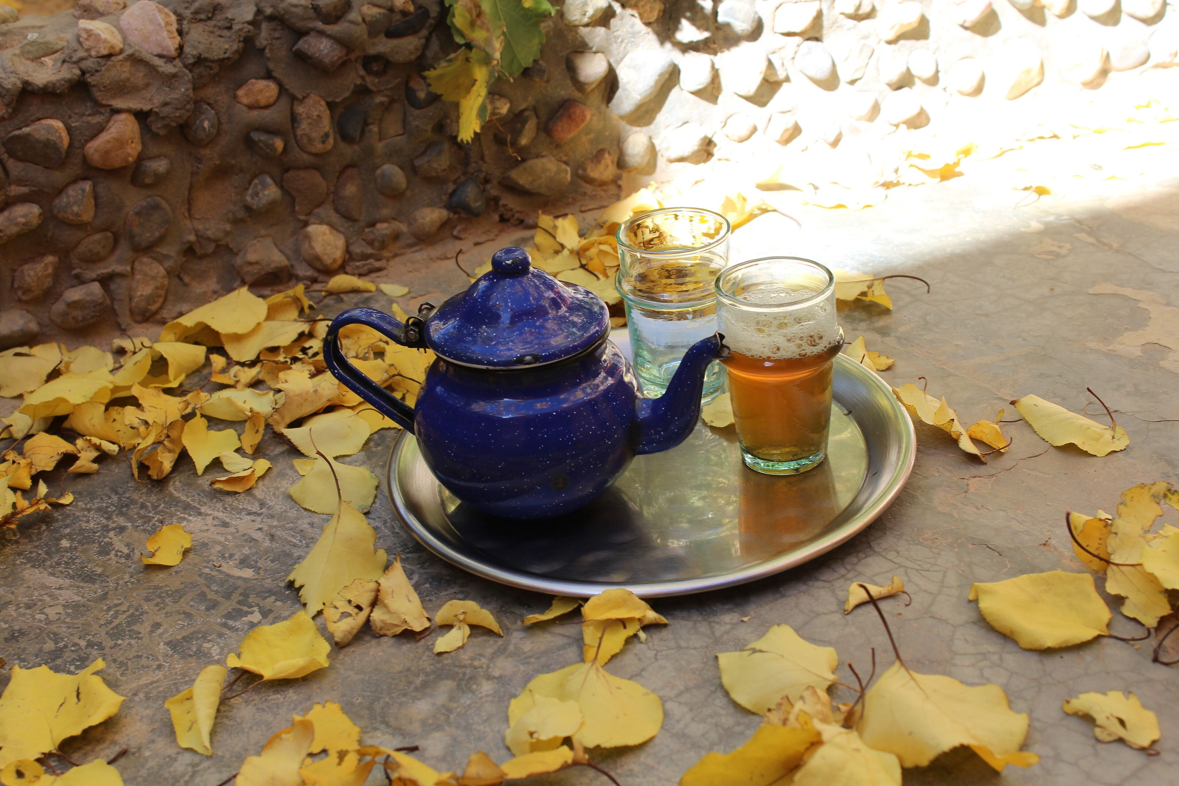 A blue teapot on a tray with a glass of tea and a glass of water.