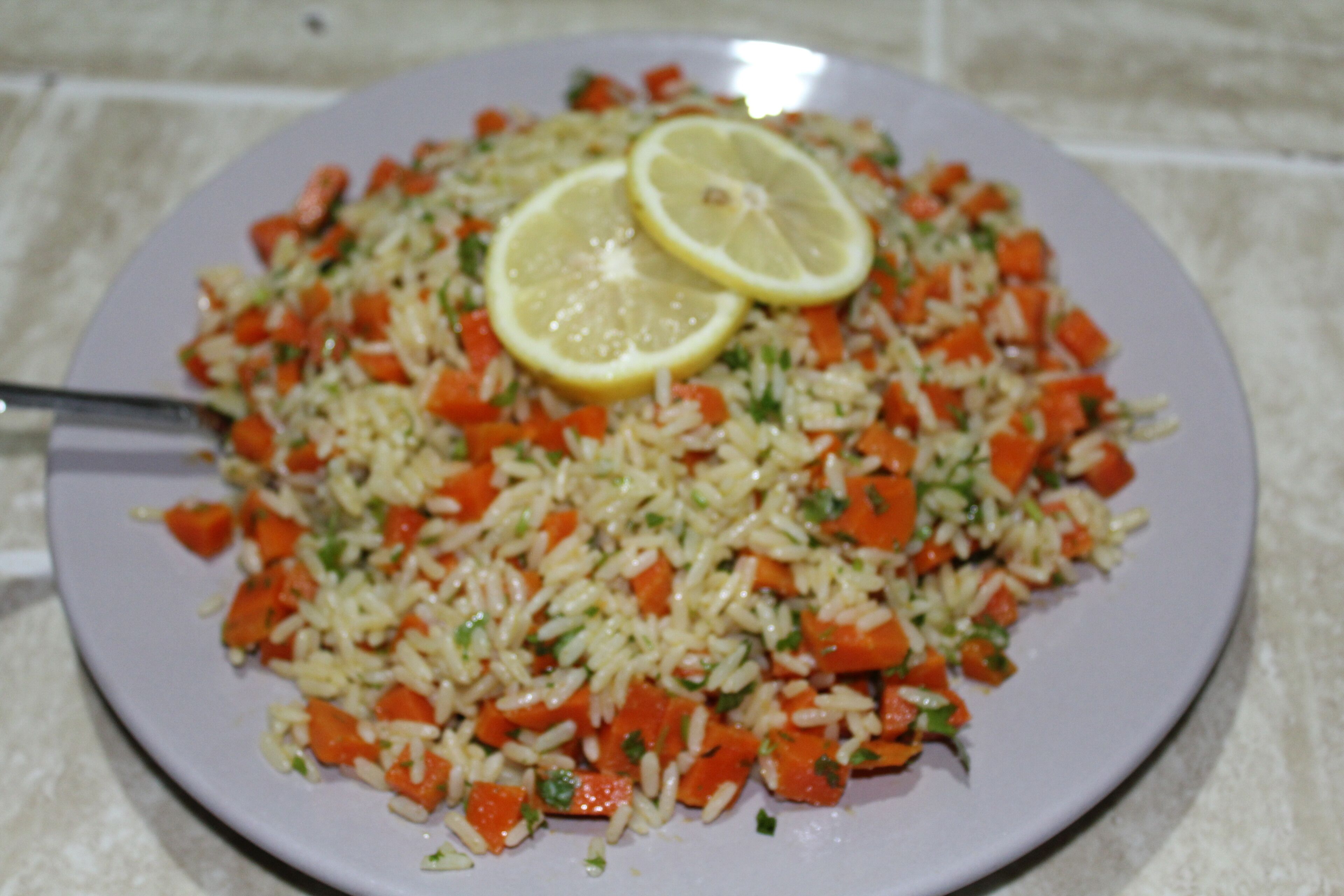 A plate of rice with carrots and lemon slices.