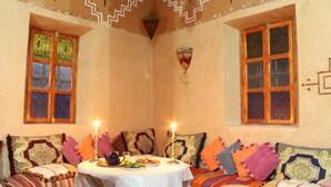 A cozy room with a round table set for dining, adorned with candles and a teapot.