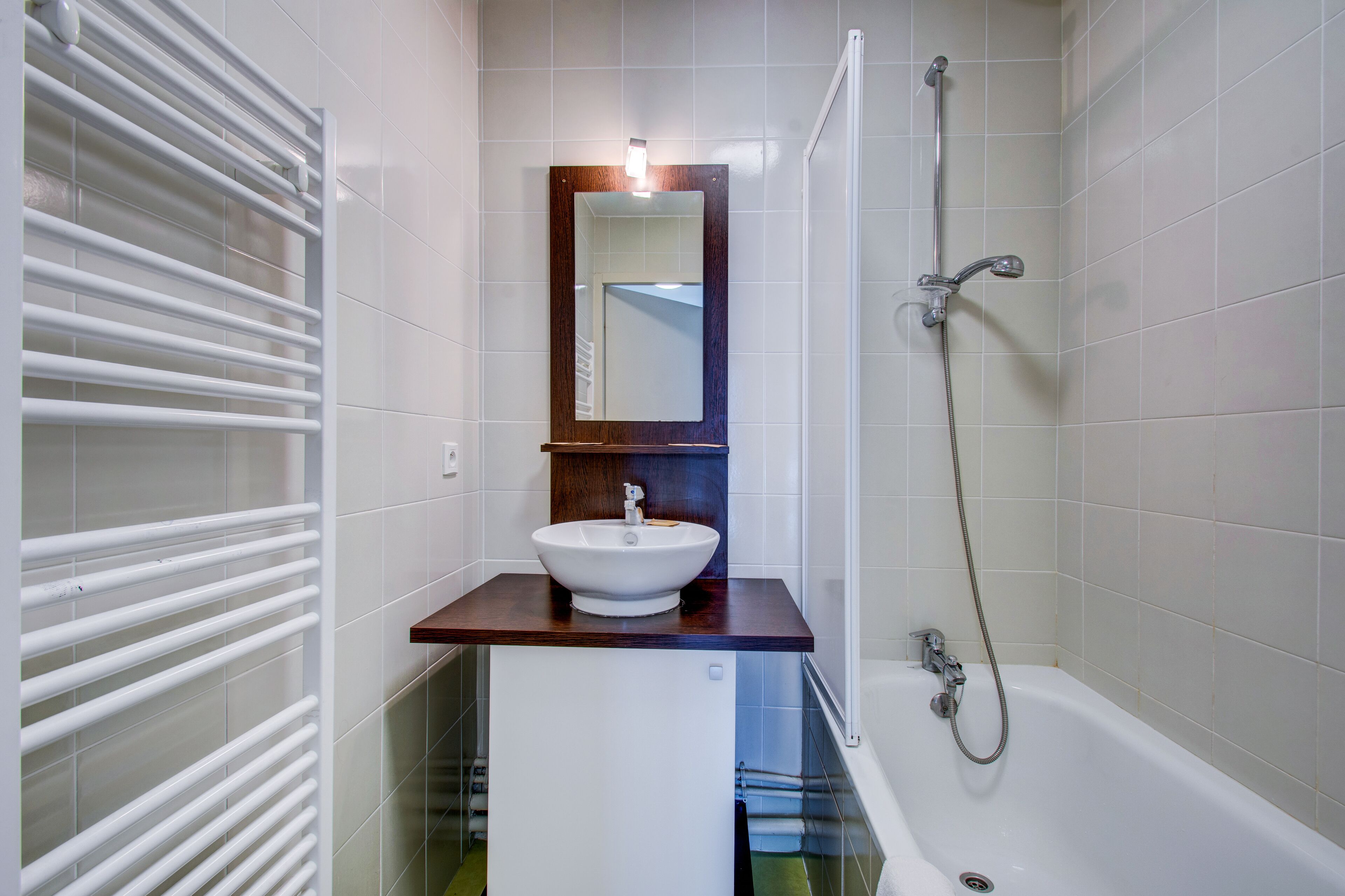 A bathroom with a white sink, a mirror, and a shower.
