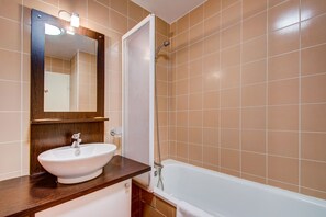 A bathroom with a white sink, a mirror, and a bathtub. - Vacancéole - Les Balcons d'Aix (Les Deserts)