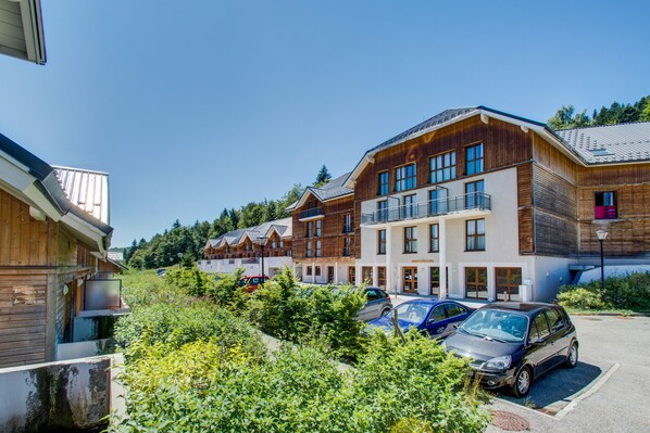 A modern building with multiple balconies, a parking area, and a lush green landscape. - Vacancéole - Les Balcons d'Aix (Les Deserts)