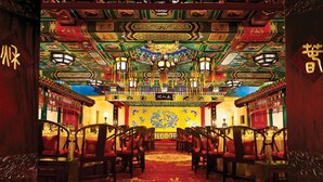 Decoración tradicional china con ornamentos elaborados, un altar central y filas de sillas.