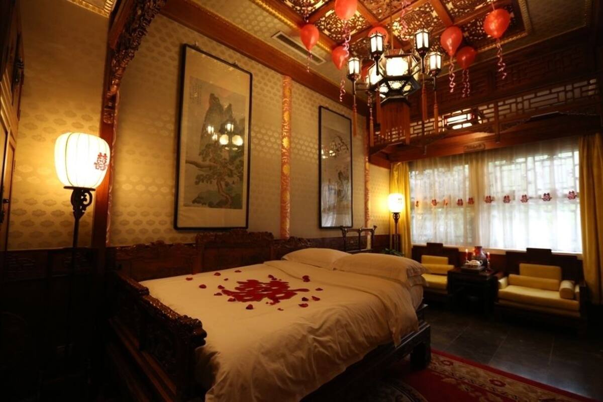 Une chambre de style traditionnel, dotée d’un grand lit, de meubles en bois richement décorés et de lanternes décoratives.