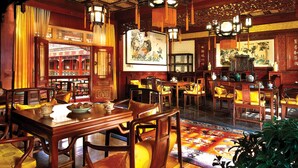 Un restaurante chino tradicional con muebles de madera, faroles colgantes y obras de arte en las paredes.