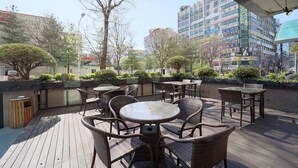 Un patio al aire libre con mobiliario de mimbre y vista a un paisaje urbano.