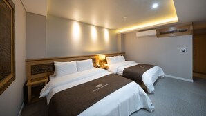 Habitación de hotel con dos camas, una mesita de noche, aire acondicionado de pared y luces empotradas en el techo.