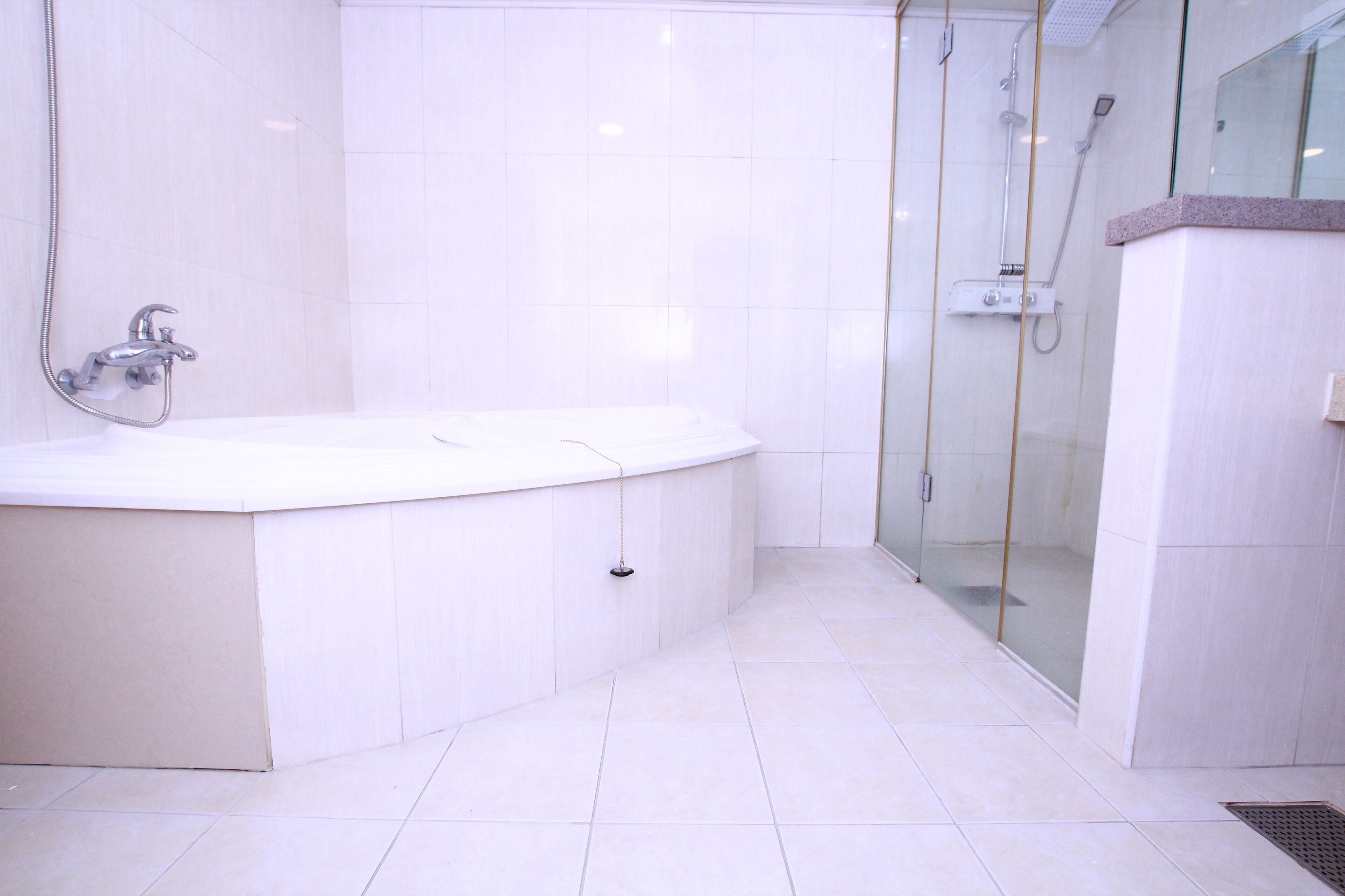 A modern bathroom with a freestanding bathtub, a glass-enclosed shower area, and a tiled floor.