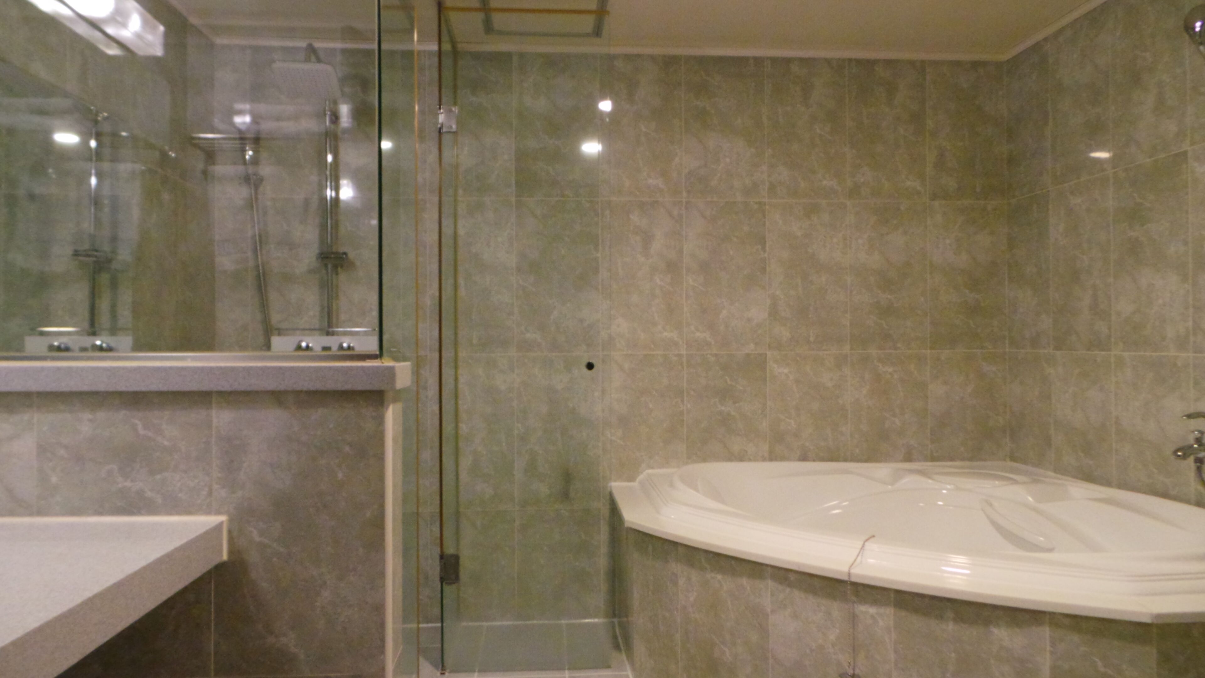 A bathroom with a glass-enclosed shower, a freestanding bathtub, and a vanity with a mirror.