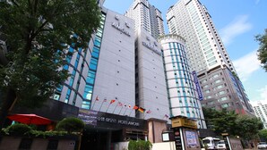 Un hotel con fachada moderna, varias banderas y una entrada destacada.