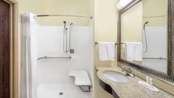 A bathroom with a shower, a sink, and a mirror.