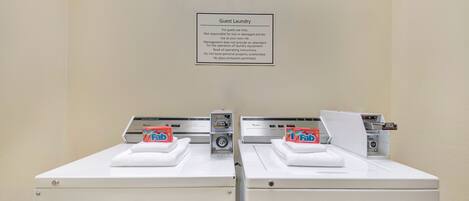A guest laundry area with two washing machines and a sign above them.