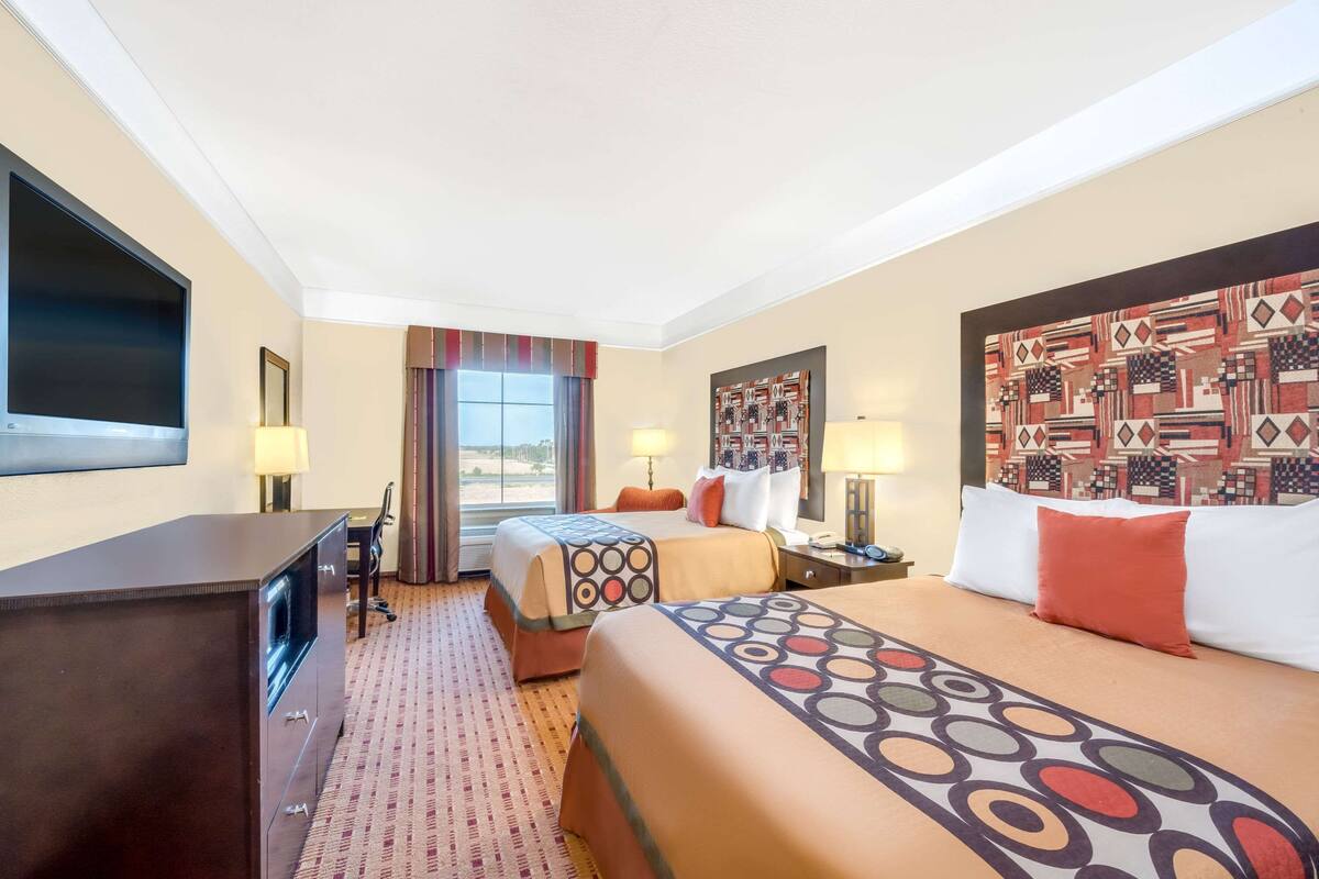 Een hotelkamer met twee bedden, een bureau, een televisie en een raam met uitzicht.