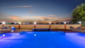 A swimming pool with a tiled edge, surrounded by lounge chairs and a wooden deck. - Super 8 by Wyndham Hidalgo/McAllen Area (Hidalgo)
