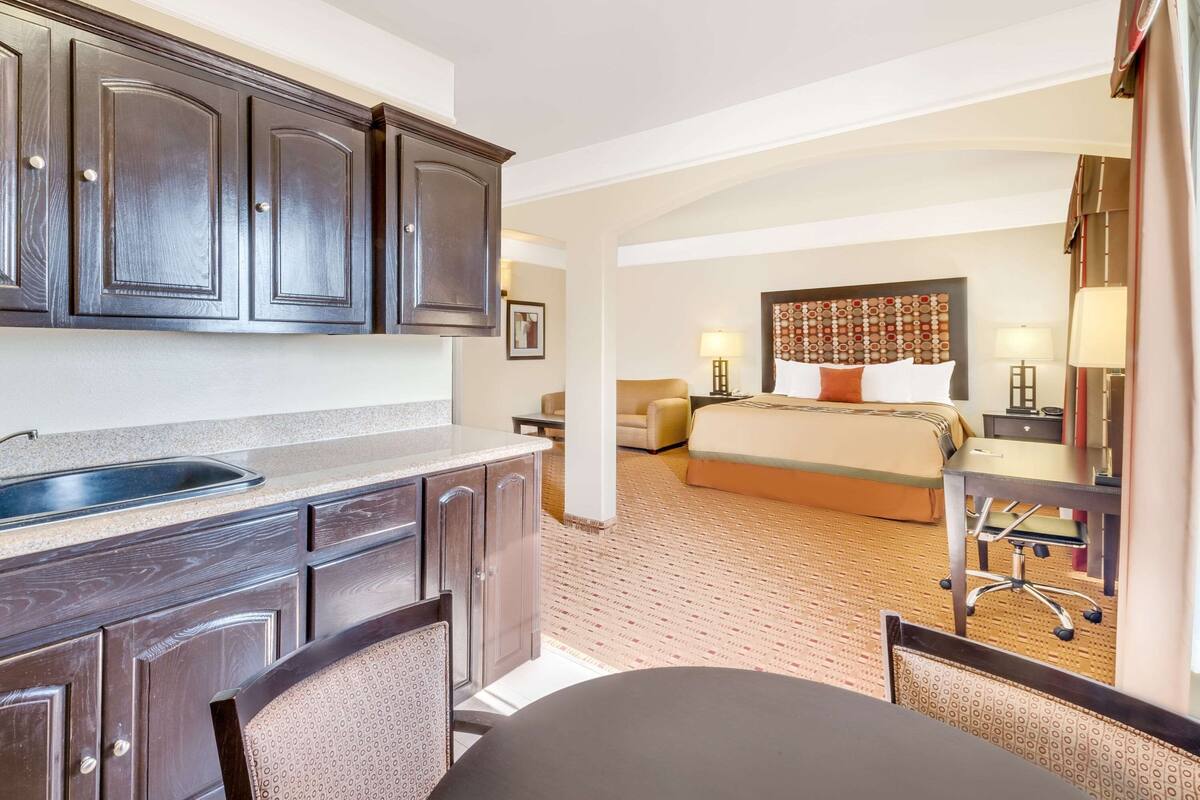 Een hotelkamer met een kitchenette, een bed, een bureau en een stoel.