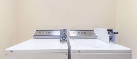 Two white front-loading washing machines in a room with plain walls.