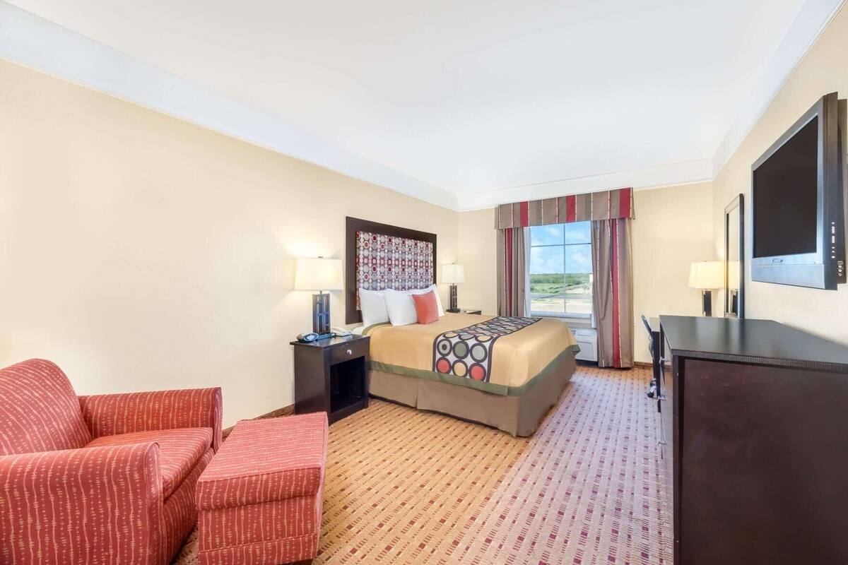 Een hotelkamer met een bed, een bureau, een stoel, een televisie en een raam met gordijnen.