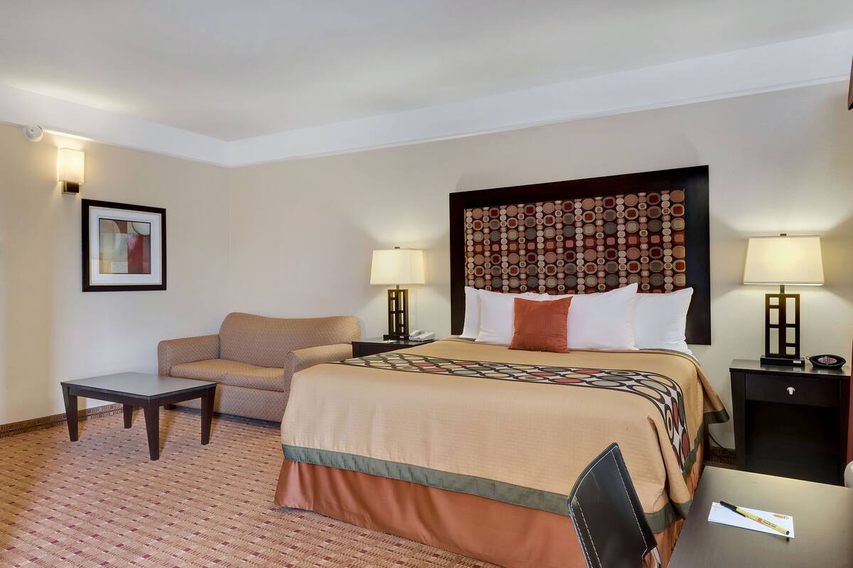 Een hotelkamer met een groot bed, een bank, een bijzettafeltje en twee bedlampjes.