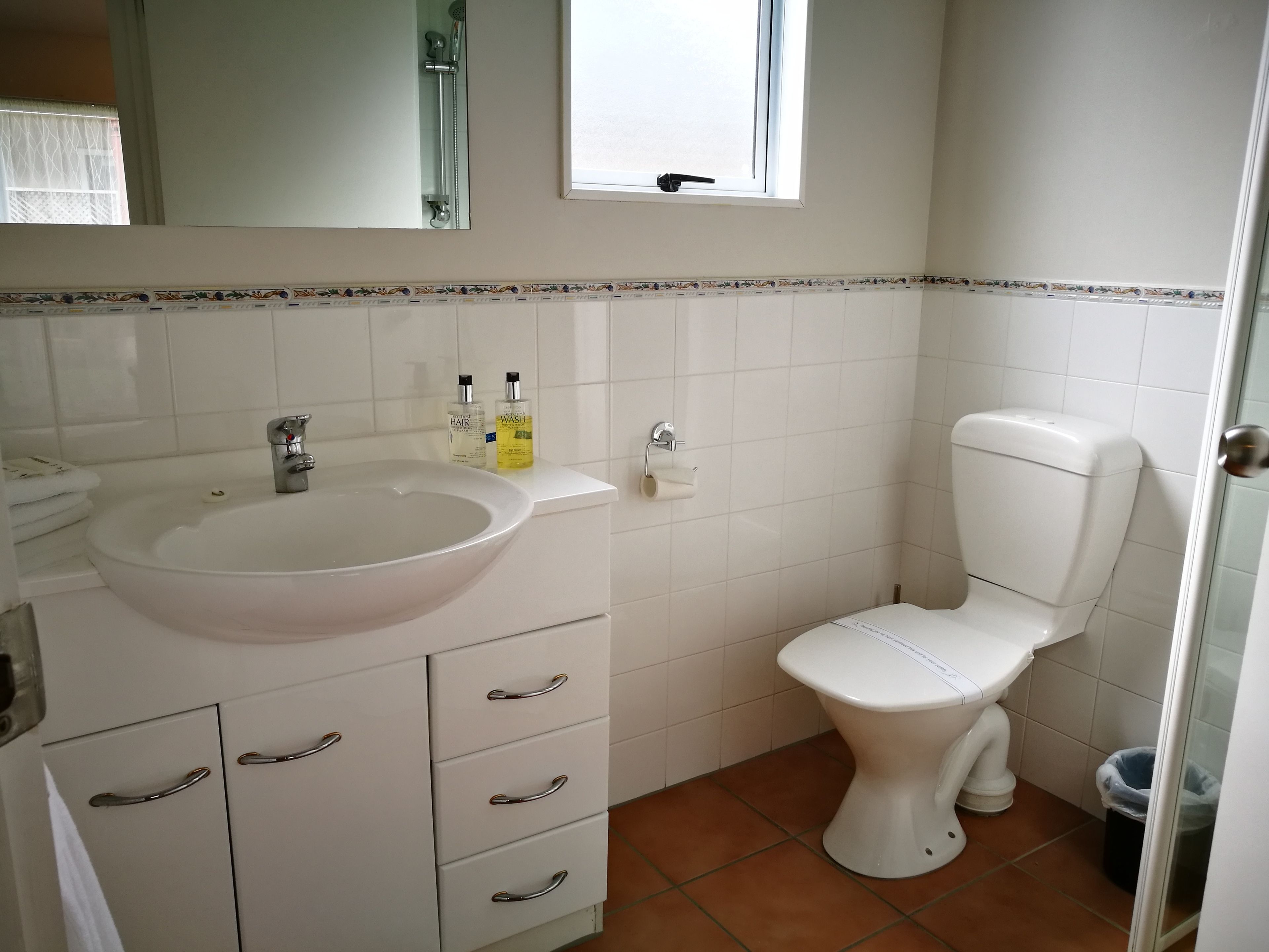 A bathroom with a white sink, a toilet, and a window.