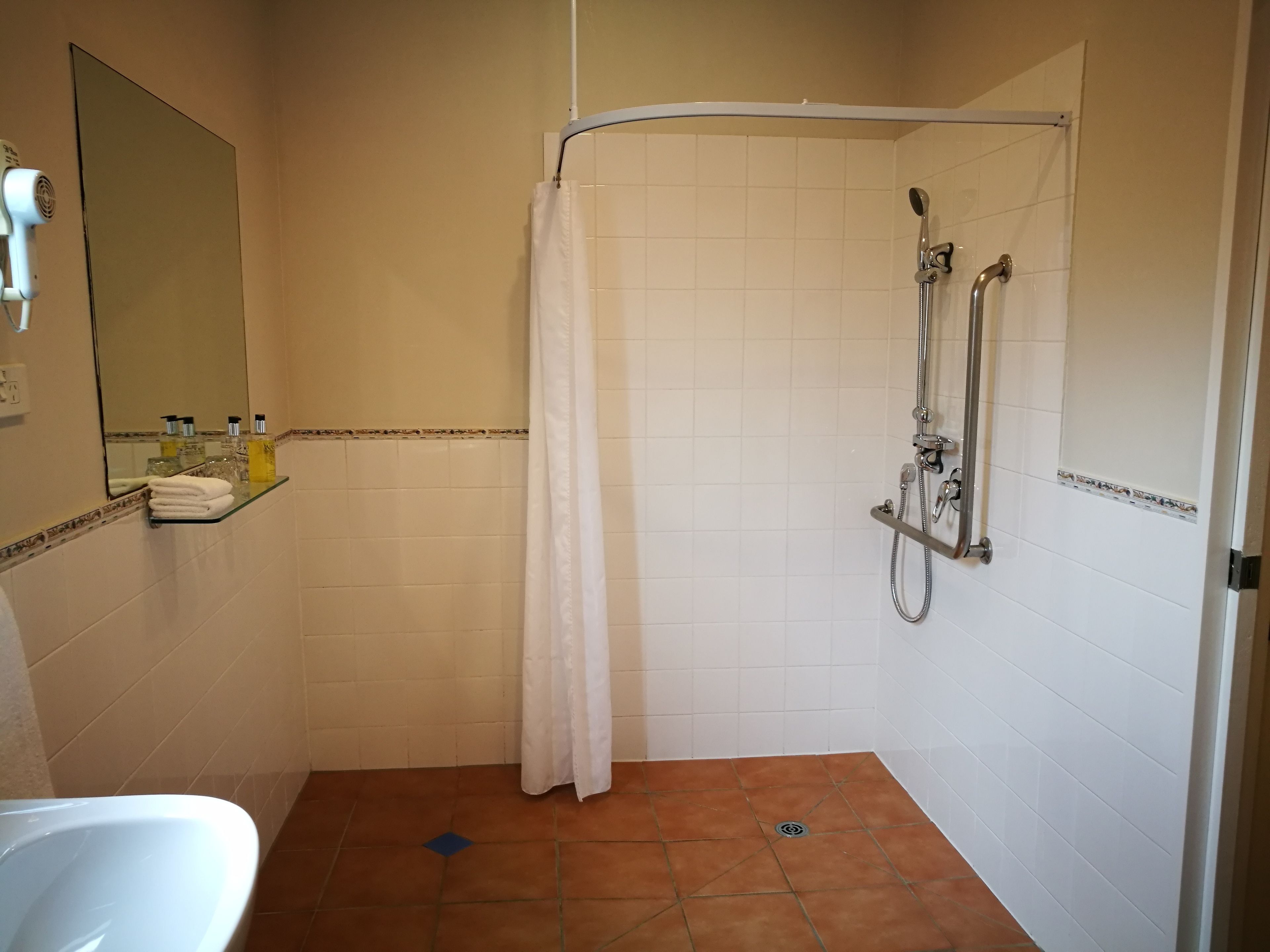 A bathroom with a shower, a sink, and a mirror.