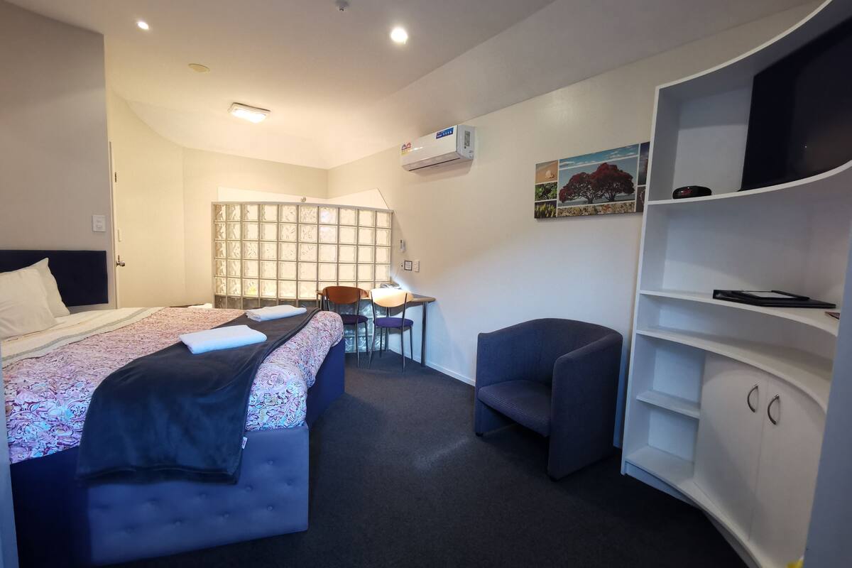 Une chambre d’hôtel comprenant un lit, un bureau, une chaise, une télévision et une armoire.