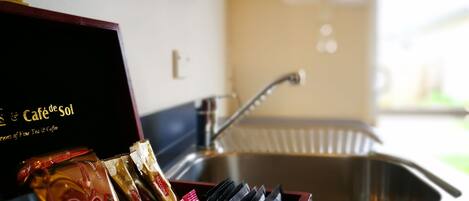 A kitchen area with a sink, a box of coffee packets, and a bottle of dish soap.