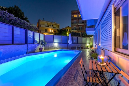 Una piscina al aire libre, sombrillas, sillones reclinables de piscina