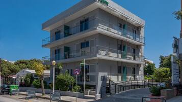 A multi-story hotel with balconies, a "No Parking" sign, and a "No Parking" sign on the street.