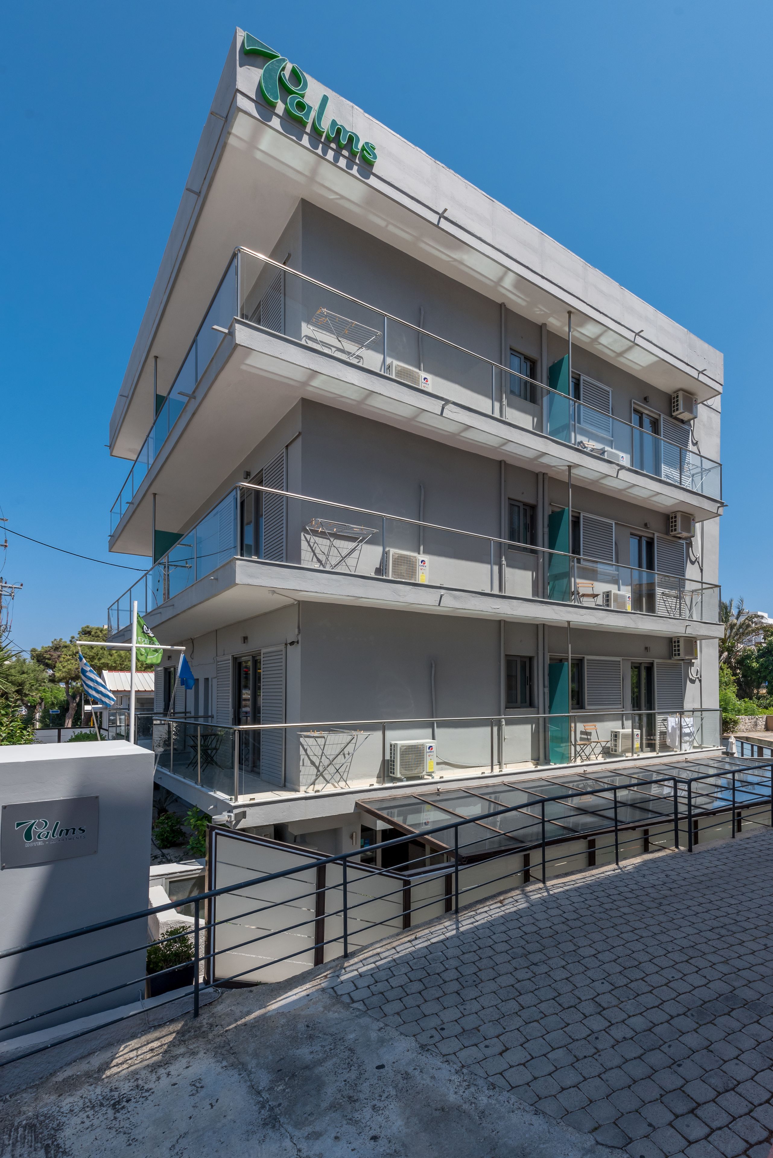 A multi-story building with balconies, air conditioning units, and a sign that reads "Palms".