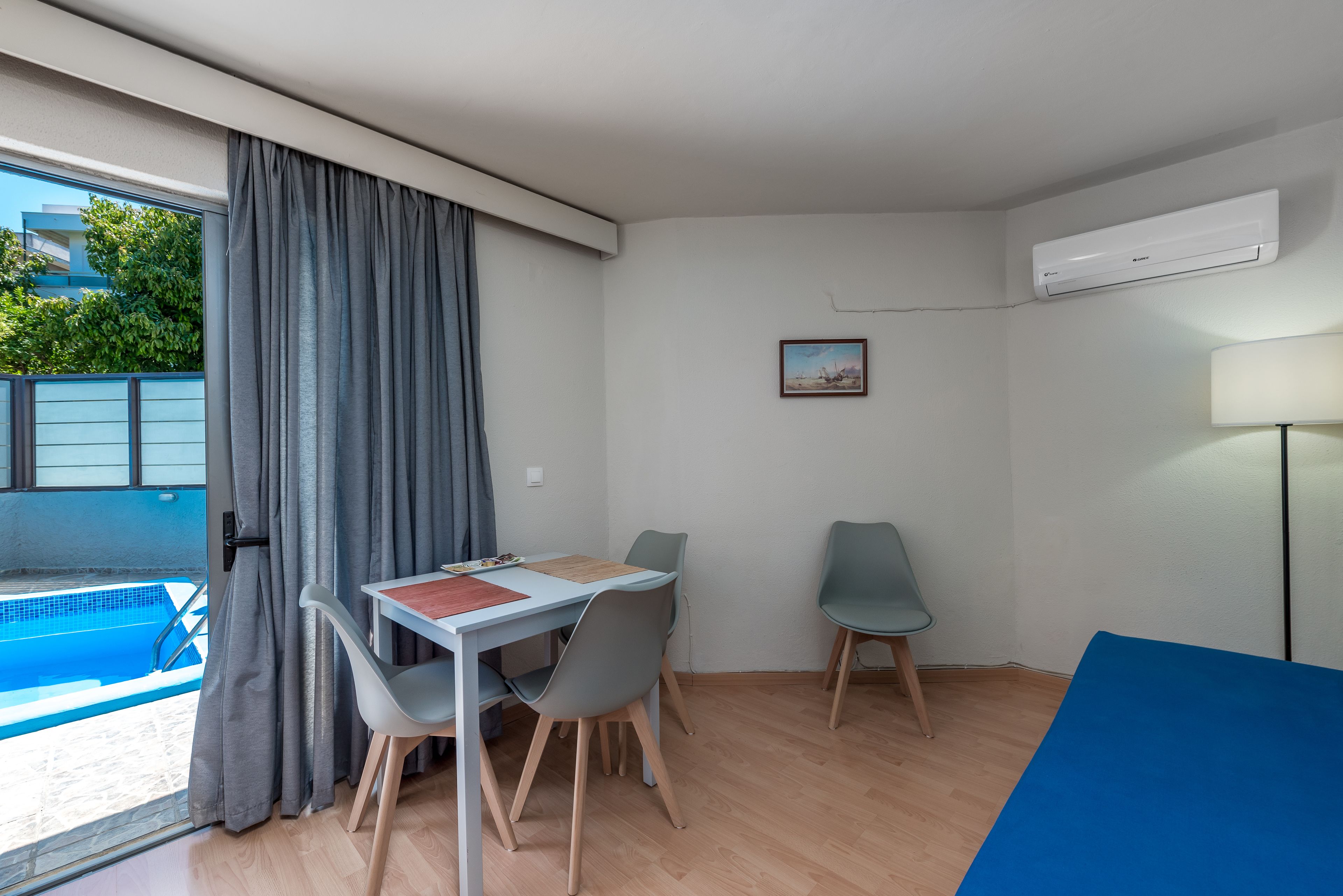 Une pièce avec une piscine, une table avec des chaises et un appareil de climatisation.
