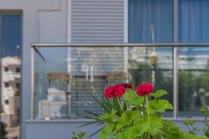 Uma varanda com vista para um edifício, um corrimão e alguma vegetação.