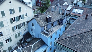 A multi-story building with a flat roof, multiple windows with shutters, and a visible balcony with outdoor furniture. - Statthotel (Zürich)