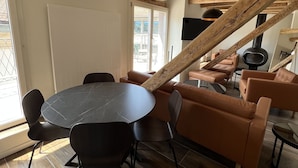 A modern living room with a wooden ceiling, a round dining table, and leather sofas. - Statthotel (Zürich)