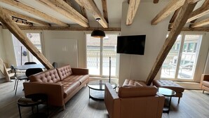 A spacious living room with wooden beams, leather sofas, and a flat-screen TV. - Statthotel (Zürich)