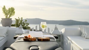 Una terraza soleada con una mesa de masajes, una bebida en un vaso y una planta en maceta.