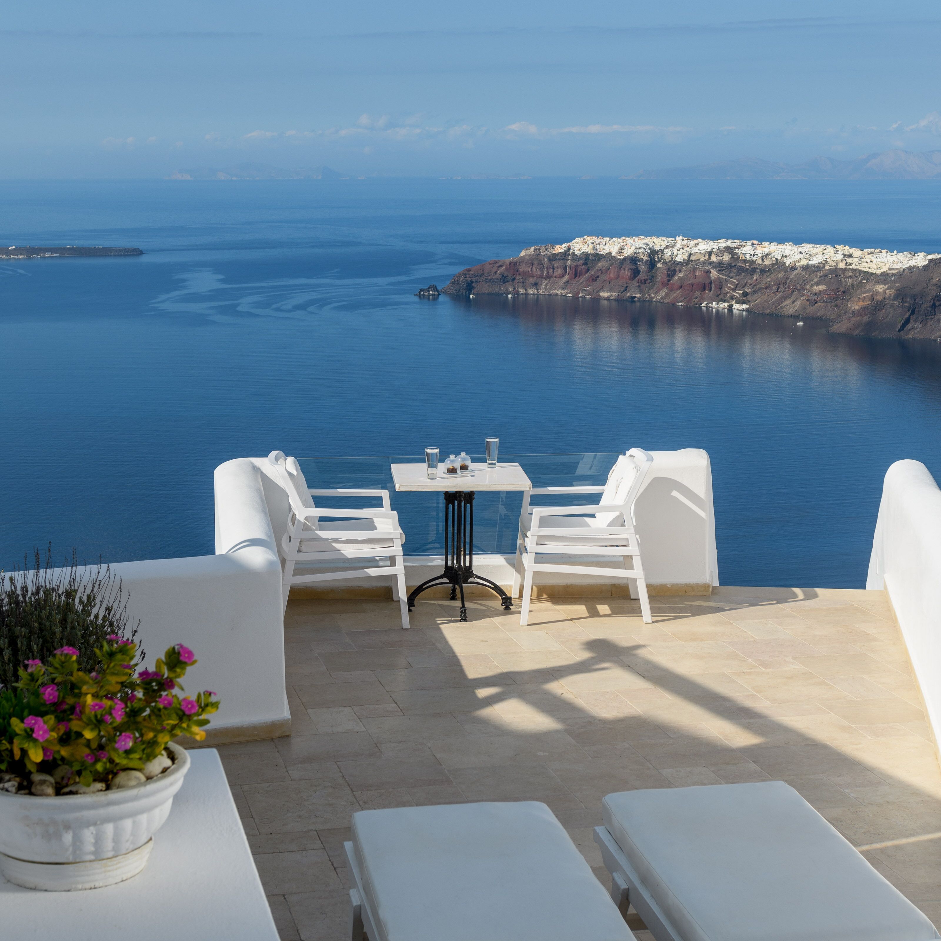 A terrace with white furniture, a table, and a potted plant.