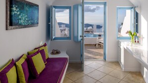 Una habitación con un sofá morado, un cuadro y vista al mar a través de una puerta.