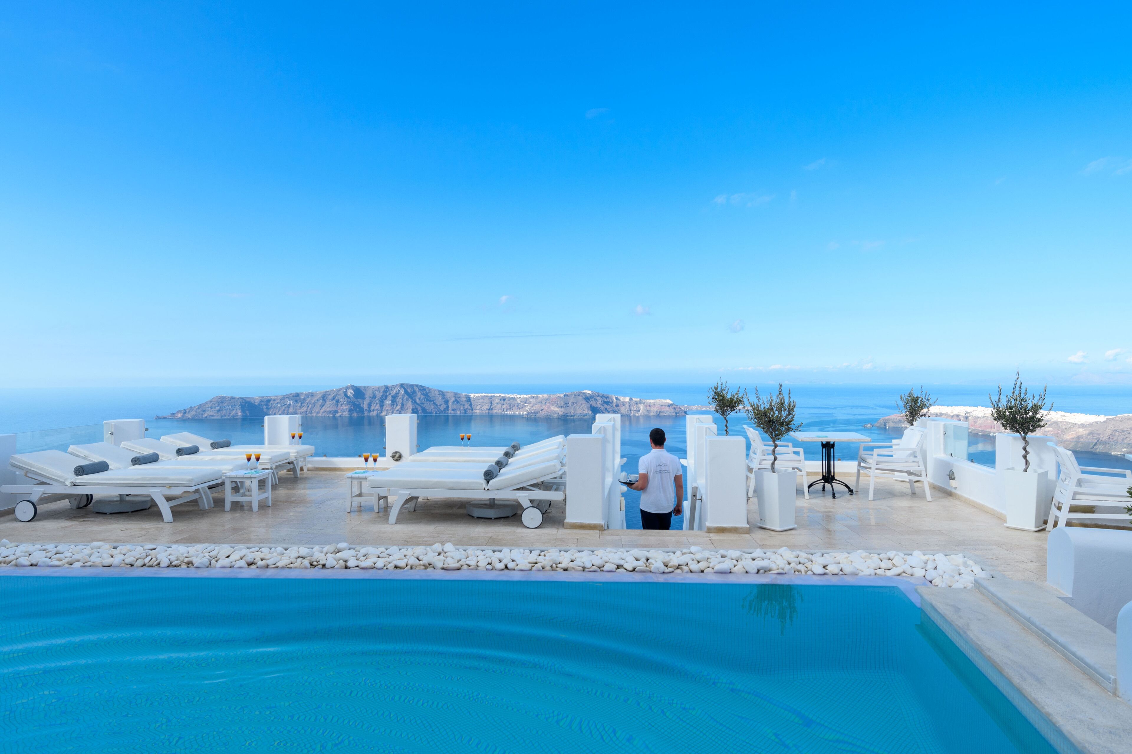 An infinity pool with lounge chairs and a view of the sea.
