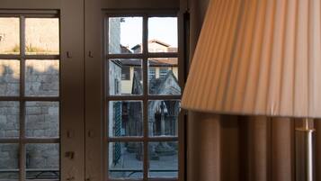 A room with a window view of a courtyard with buildings and a lamp.