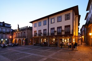 A historic building with a courtyard, outdoor seating, and a statue.