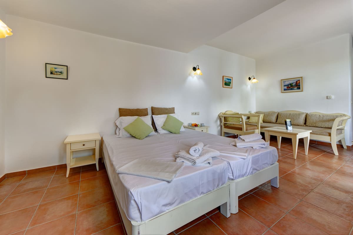 Une chambre à coucher comprenant un lit, des tables de chevet, un canapé et une petite table avec une lampe.