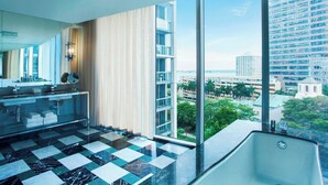 A modern hotel bathroom with a checkered marble floor, a large window, and a view of the cityscape. - W Miami (Miami)